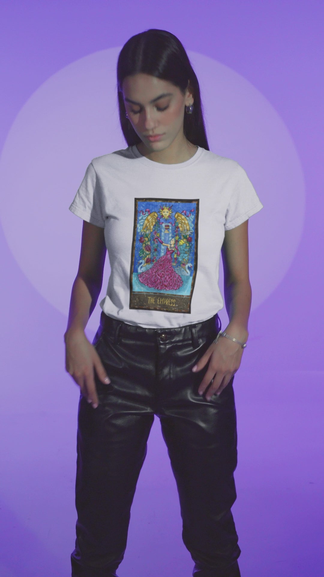 A video featuring a stylish woman wearing a white The Empress Tarot Card T-Shirt with leather pants