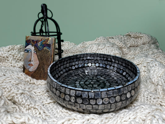 A Curvy Round Mother of Pearl Tray on a blanket, with decorations in the back