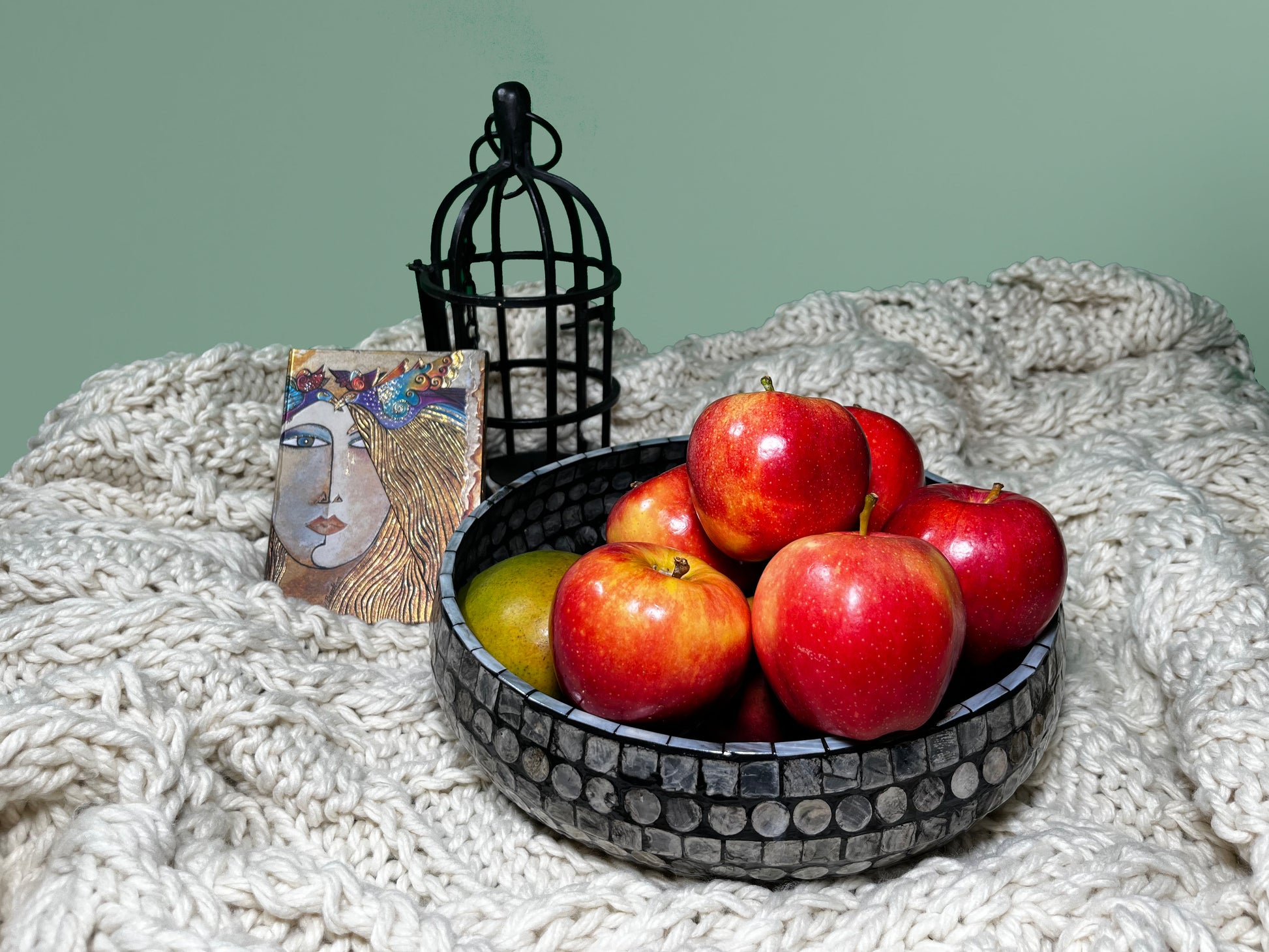 Curvy Round Mother of Pearl Tray on a blanket, with decoration in the back and apples inside the tray