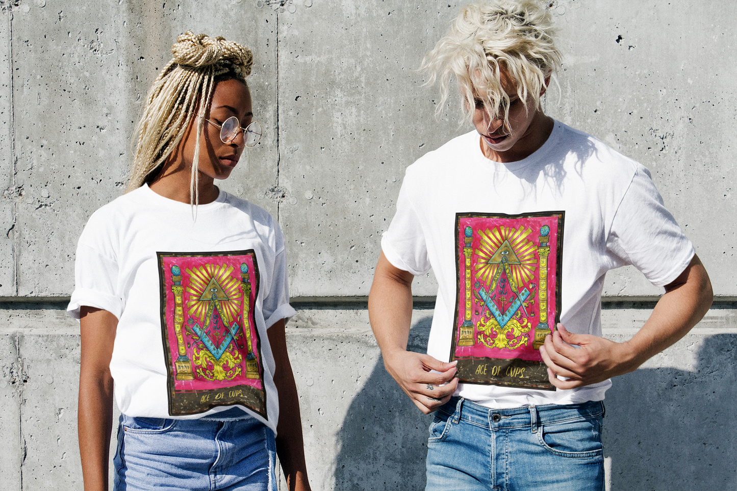 Black couple in ace of cups tarot card t-shirt, blue jeans posing in front of a cement wall