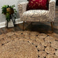 Circle Seagrass Rug in front of a chair with two pillows and a plant