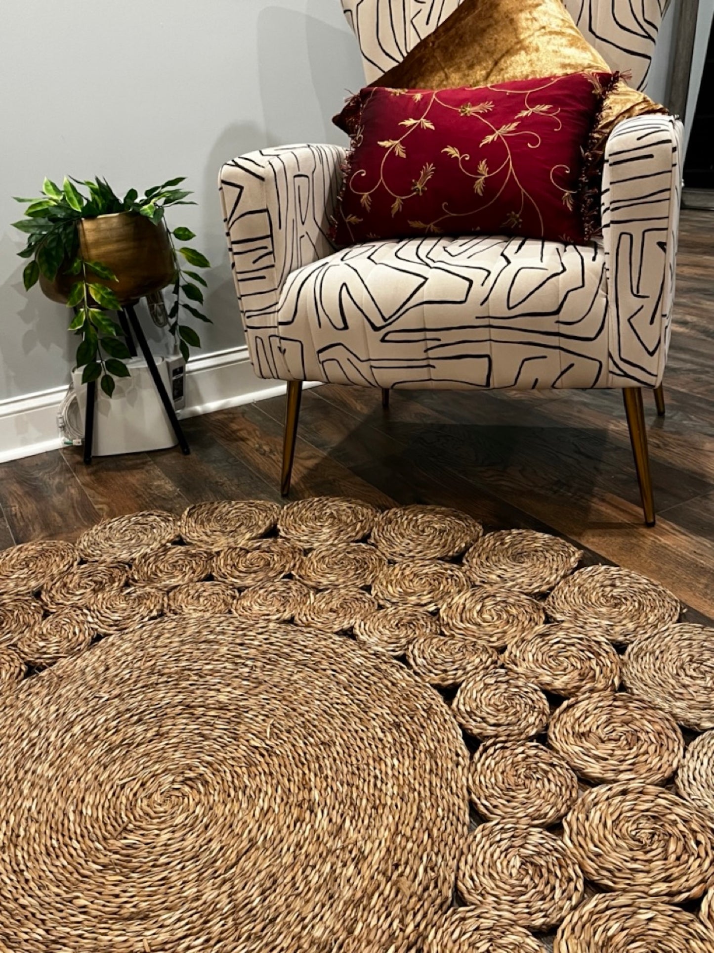 Circle Seagrass Rug in front of a chair with two pillows and a plant