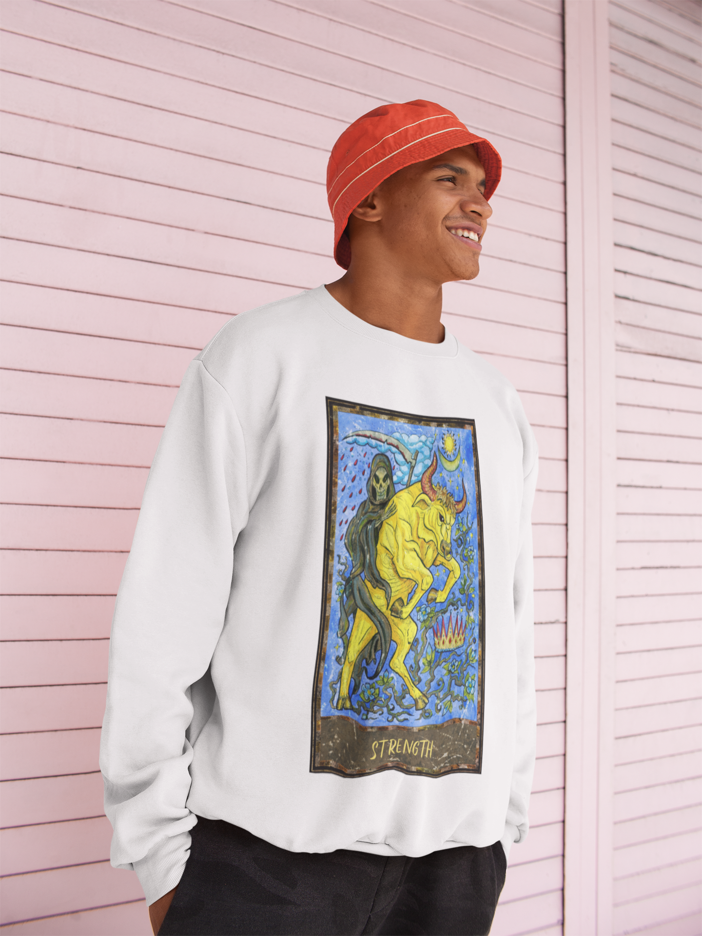 A man wearing an orange bucket hat, white Strength Tarot Card Sweatshirt, black pants