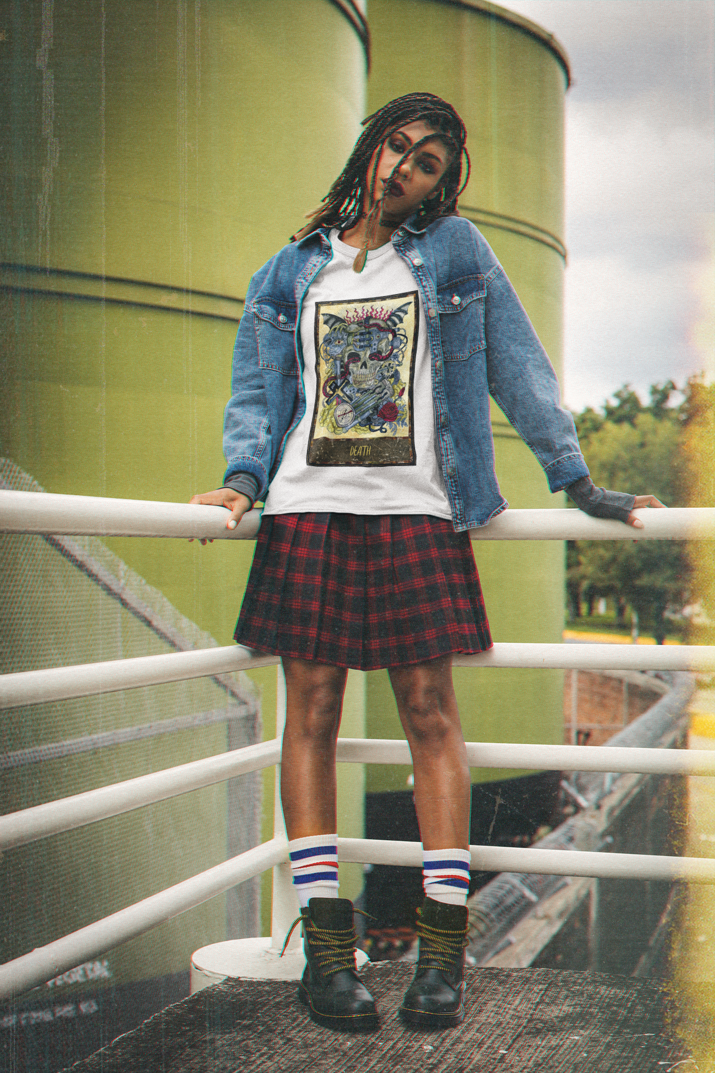 A woman wearing a white Death Tarot Card T-Shirt with a blue denim jacket, black and red checkered skirt, white socks and black boots