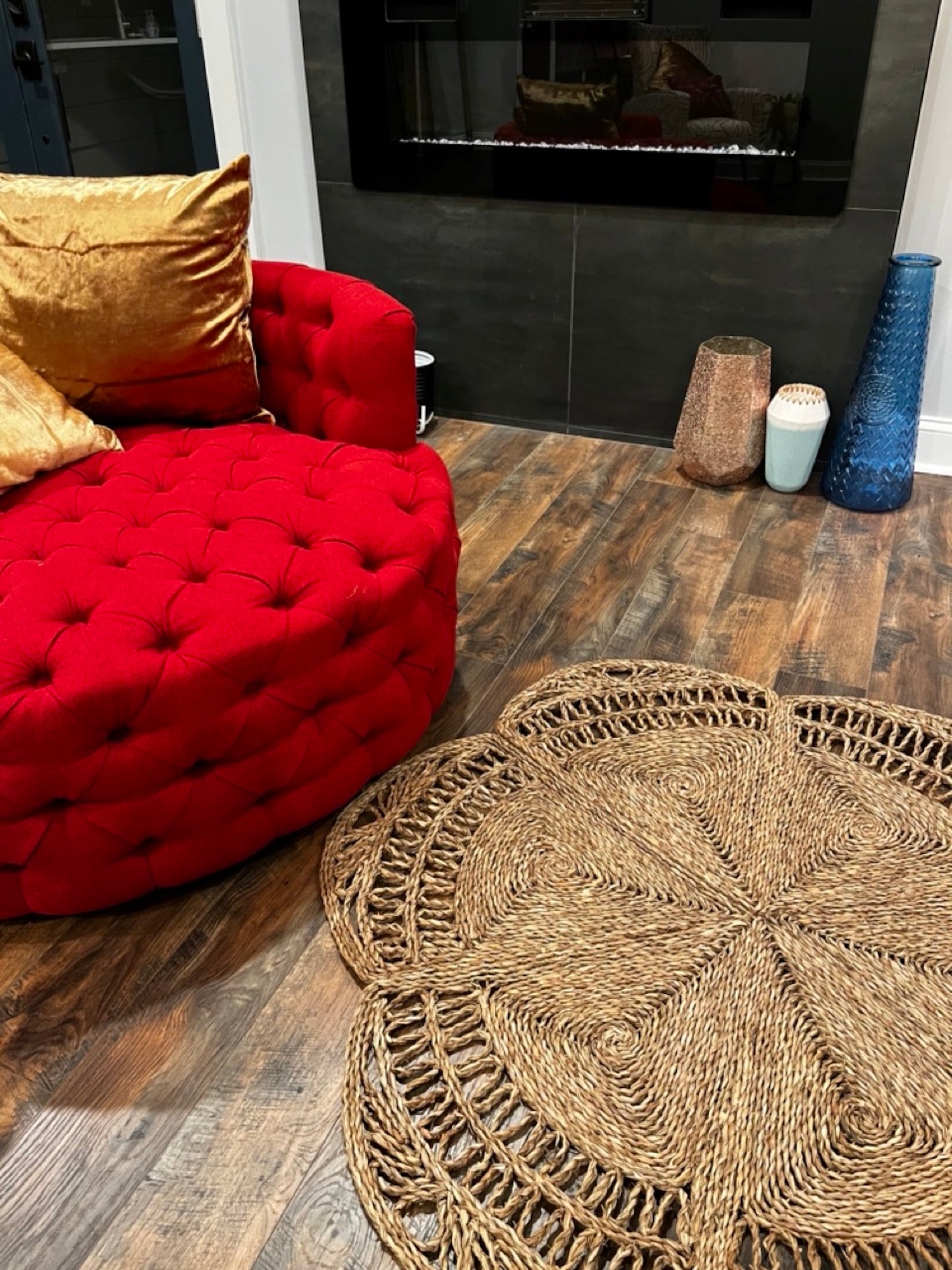 Flower Seagrass Rug in the living room next to the faux fire place and a red chair