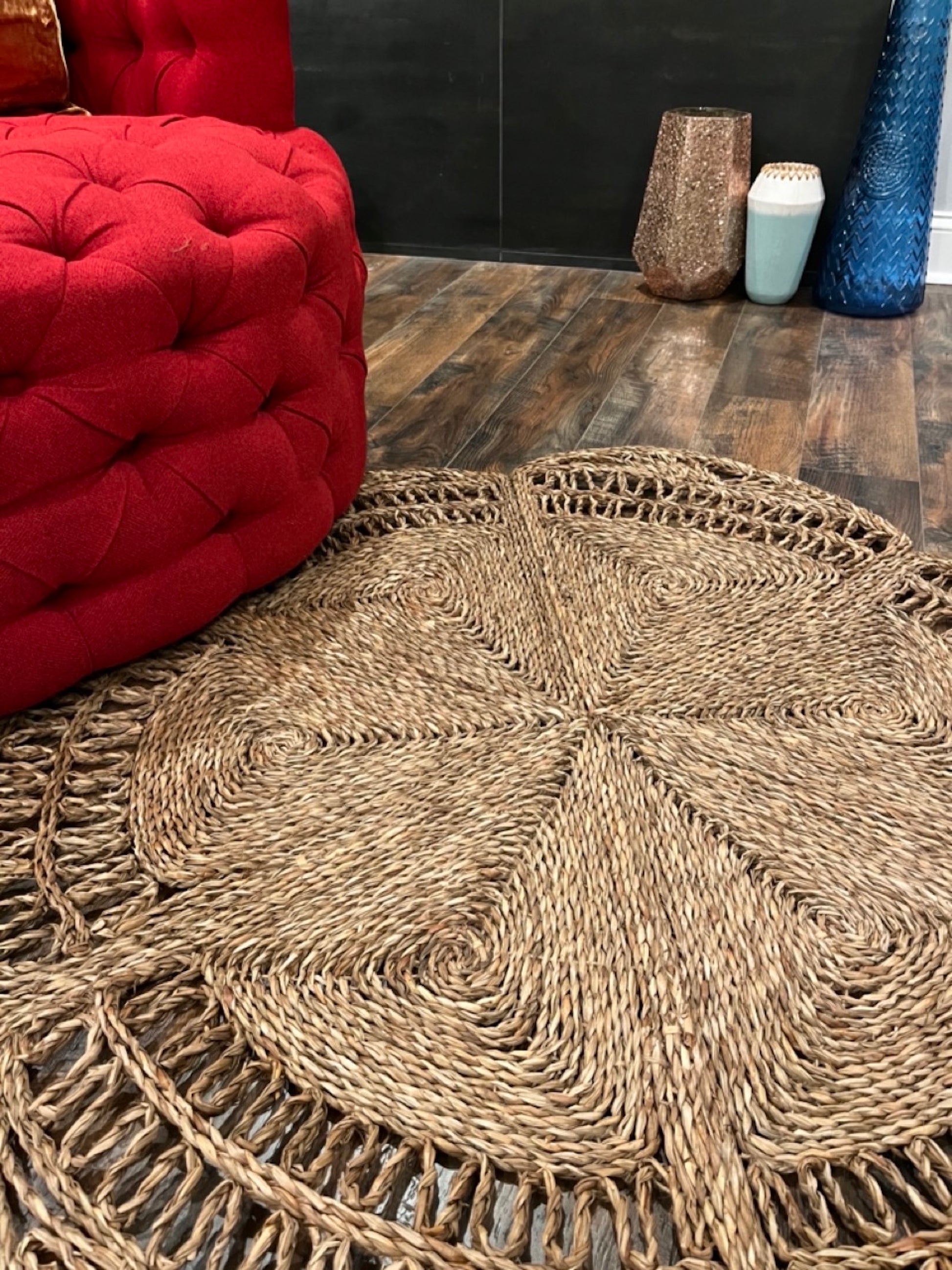 A semi close up shot of the Flower Seagrass Rug next to the red chair