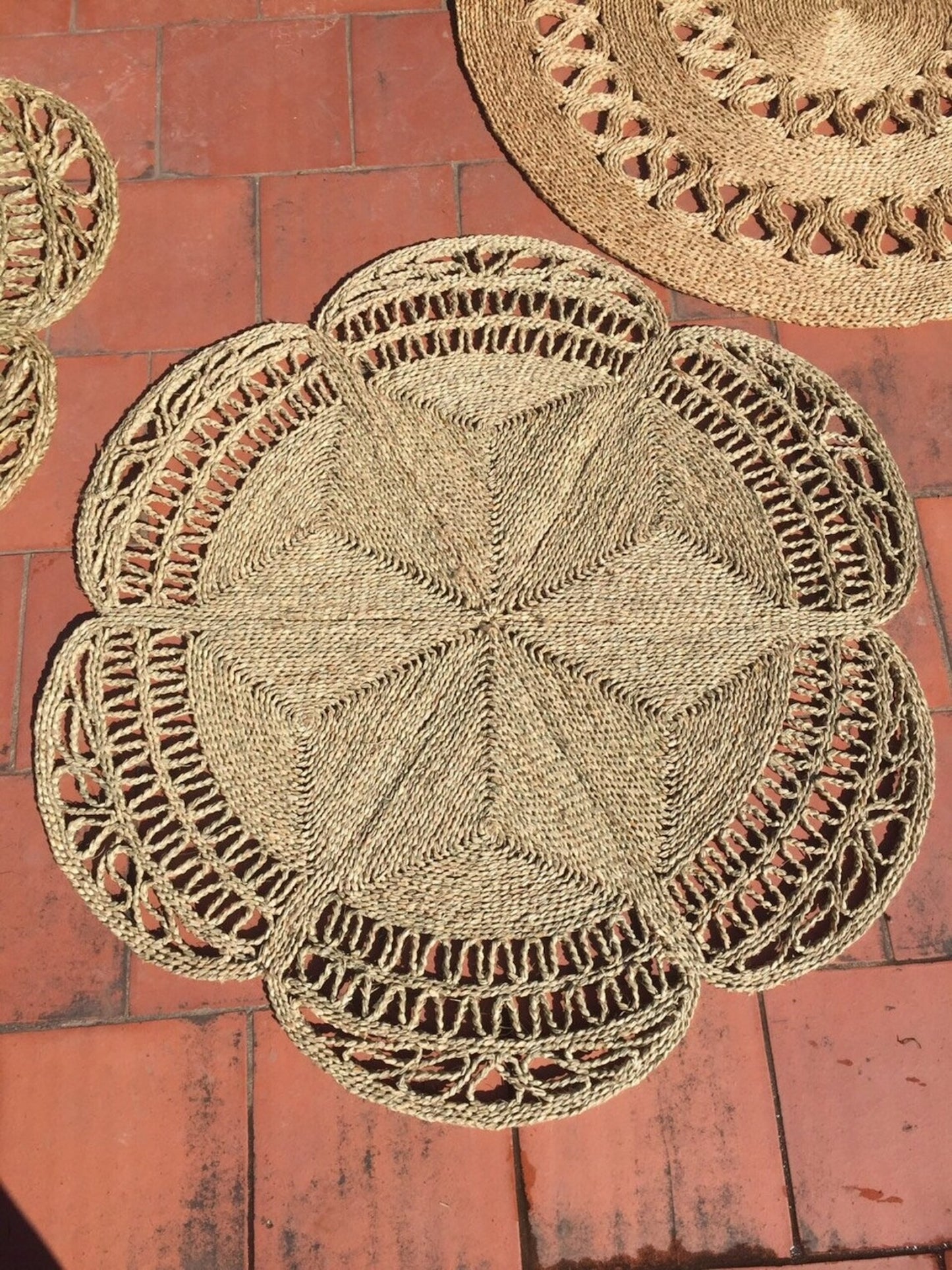 Flower Seagrass Rug next to other seagrass rugs in the sun