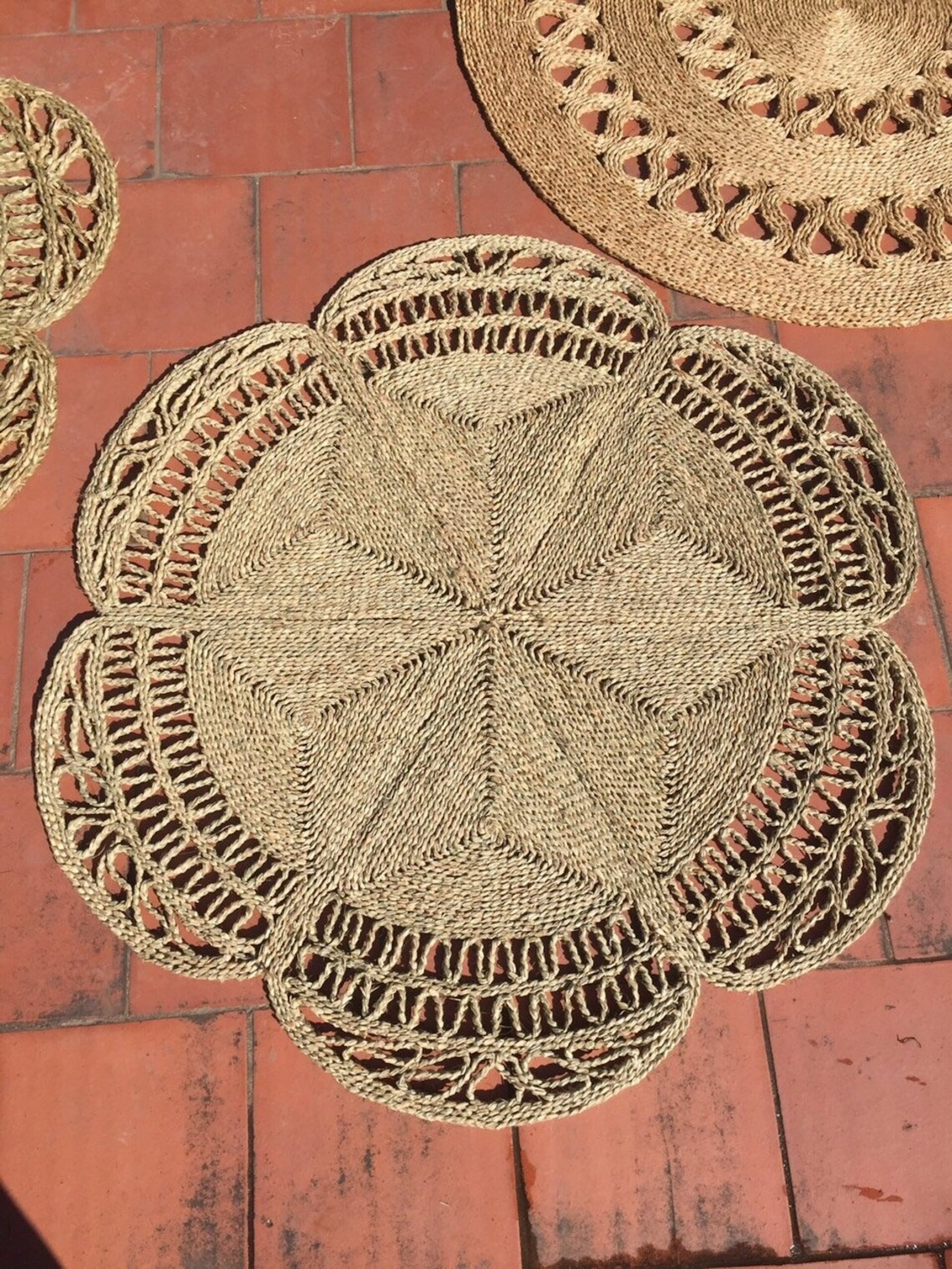 Flower Seagrass Rug next to other seagrass rugs in the sun