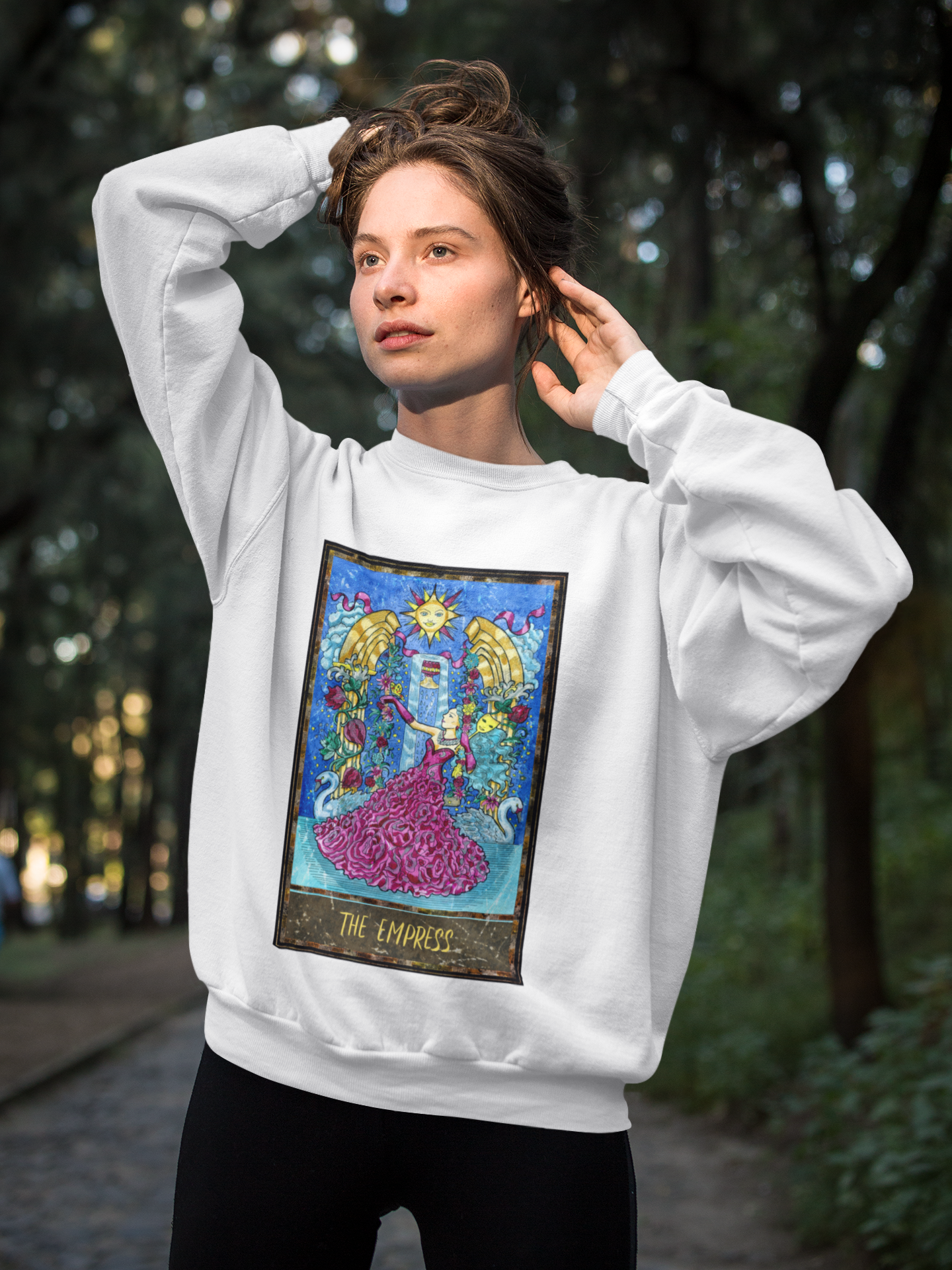 A girl looking at the sun wearing a white The Empress Tarot Card Sweatshirt and black pants