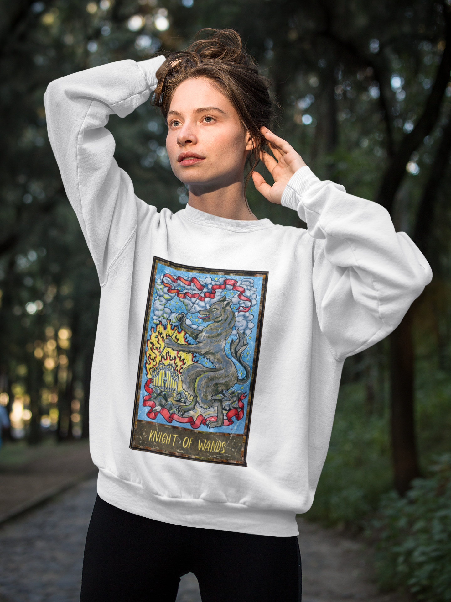 A woman wearing a white Knight of Wands Tarot Card Sweatshirt, and black pants