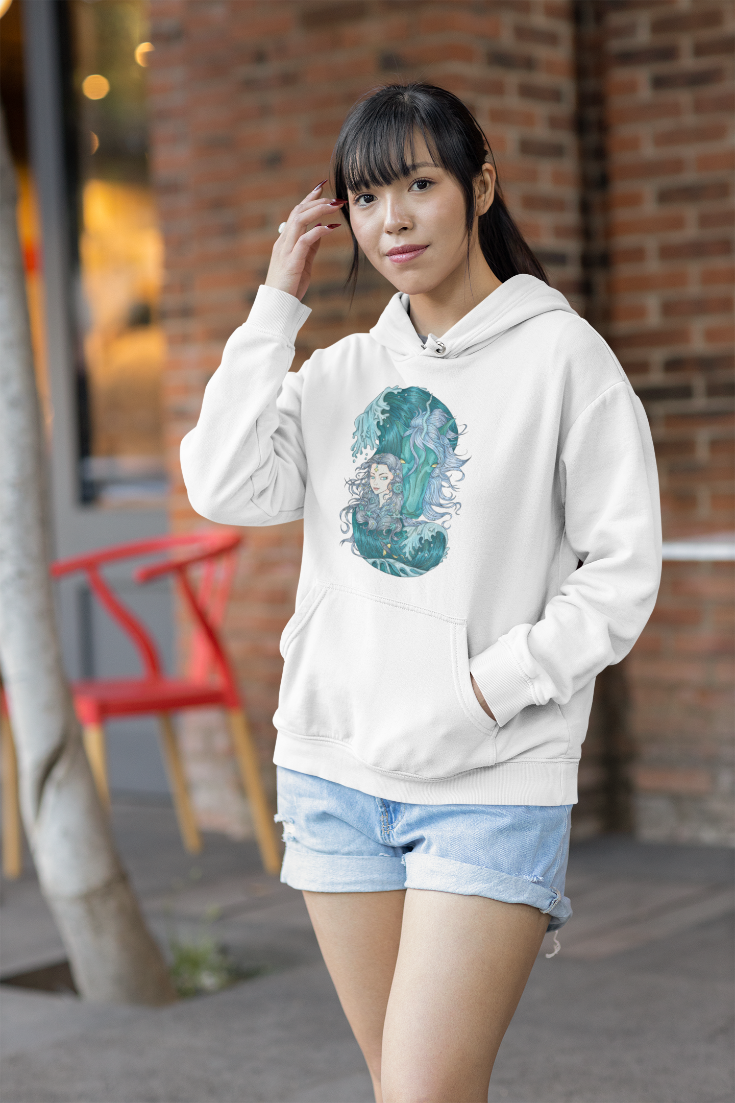 A young long haired woman posing on the street wearing a white Icy Blue Princess and Magic Unicorn Hoodie and blue shorts