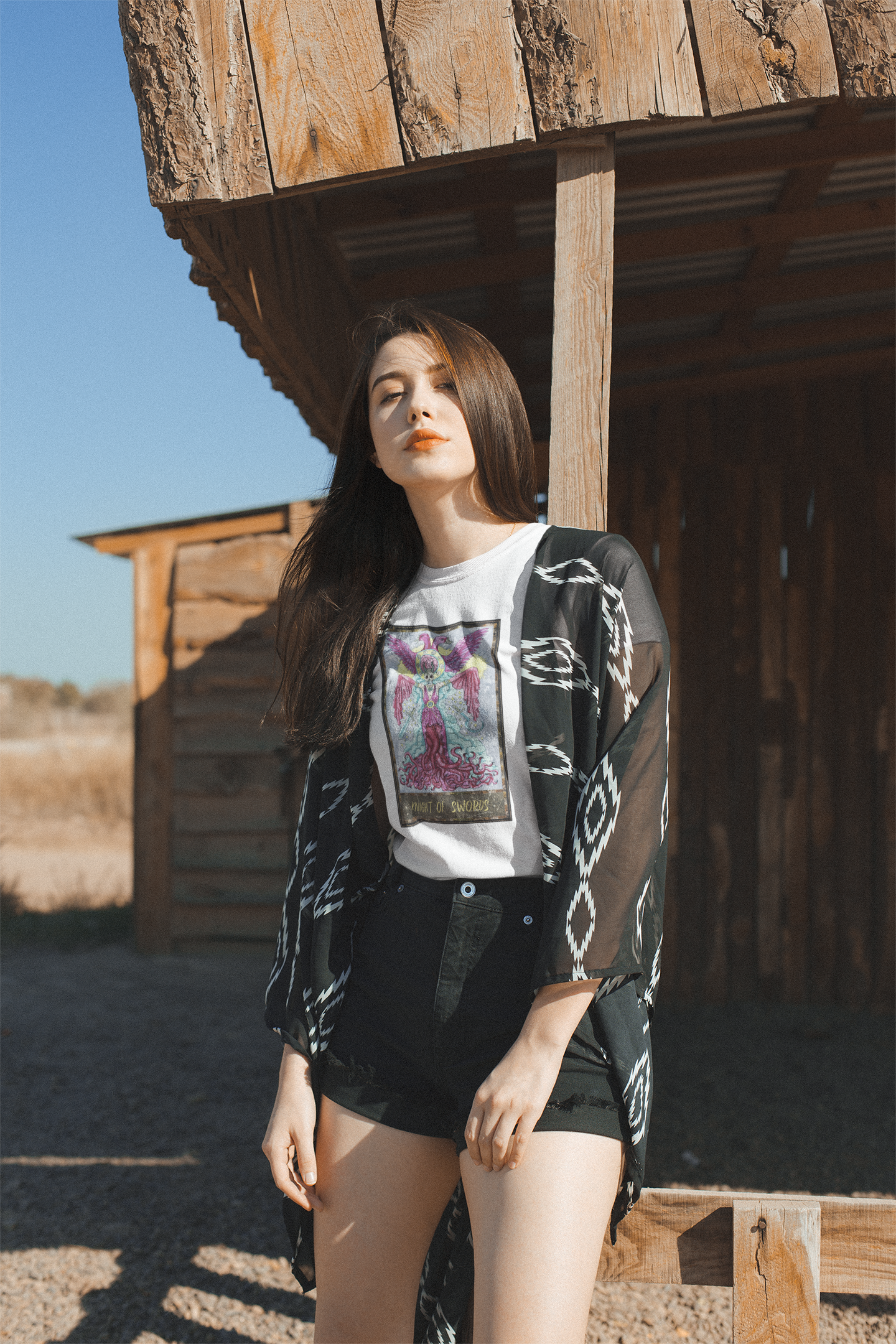 A young woman wearing a white Knight of Swords Tarot Card T-shirt, a patterned kimono, and black shorts