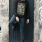 A young boy wearing a black Ace of Wands Tarot Card Sweatshirt outside of a white collar shirt, dark blue jeans, and black boots