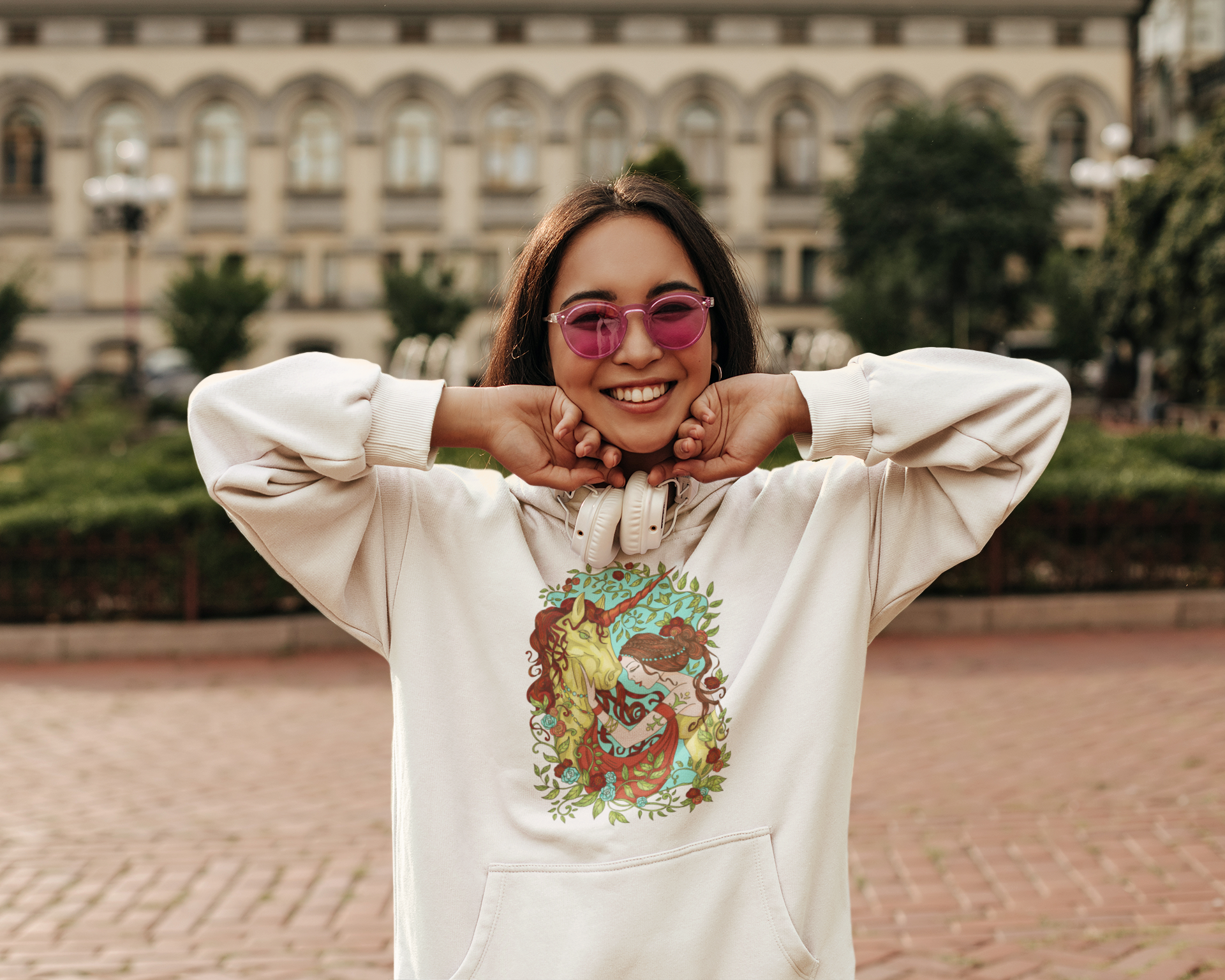 A woman with pink sunglasses and headphones wearing a white Russet Princess and Magic Unicorn Hoodie