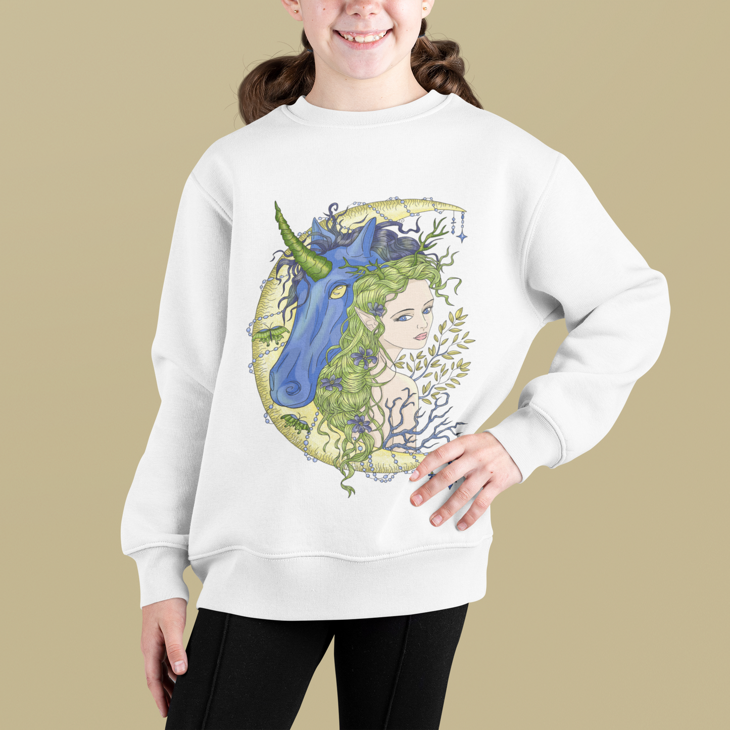 A smiling little girl posing in a studio with beige background wearing a white Chartreuse Princess and Magic Unicorn Sweatshirt and black pants