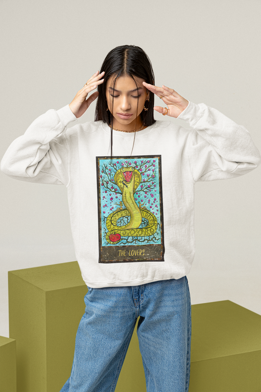 A woman wearing a white The Lovers Tarot Card Sweatshirt and blue jeans