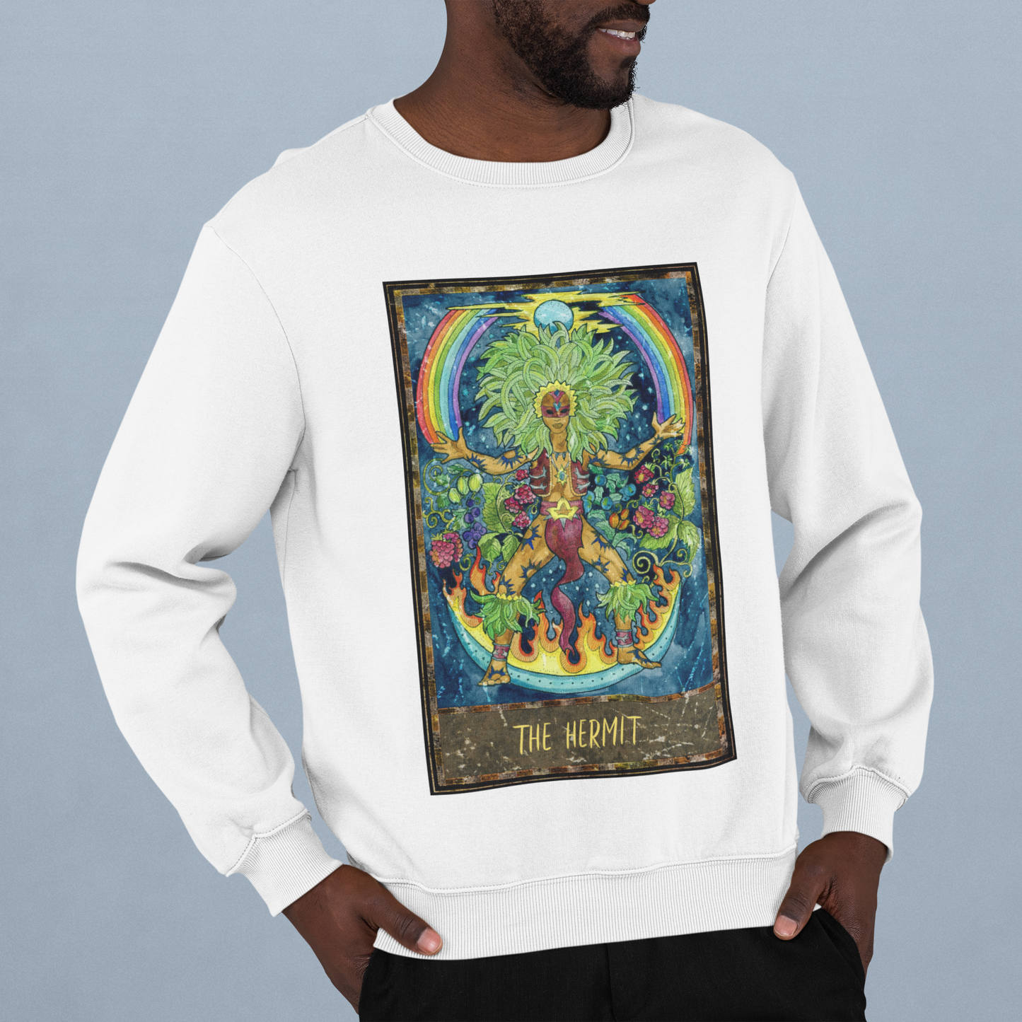 A man wearing white The Hermit Tarot Card Sweatshirt and black pants standing in a studio