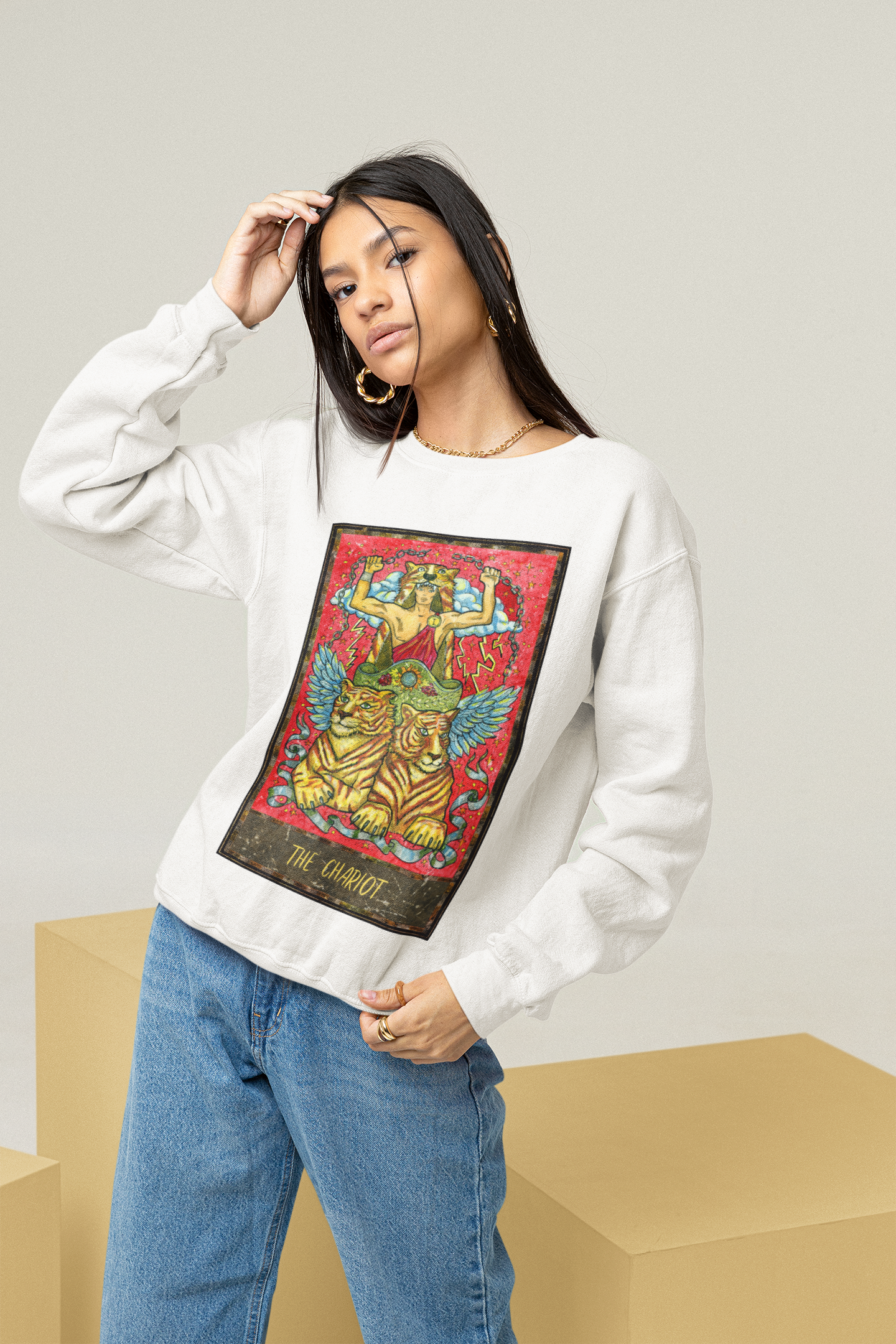 A woman wearing a white The Chariot Tarot Card Sweatshirt and blue jeans