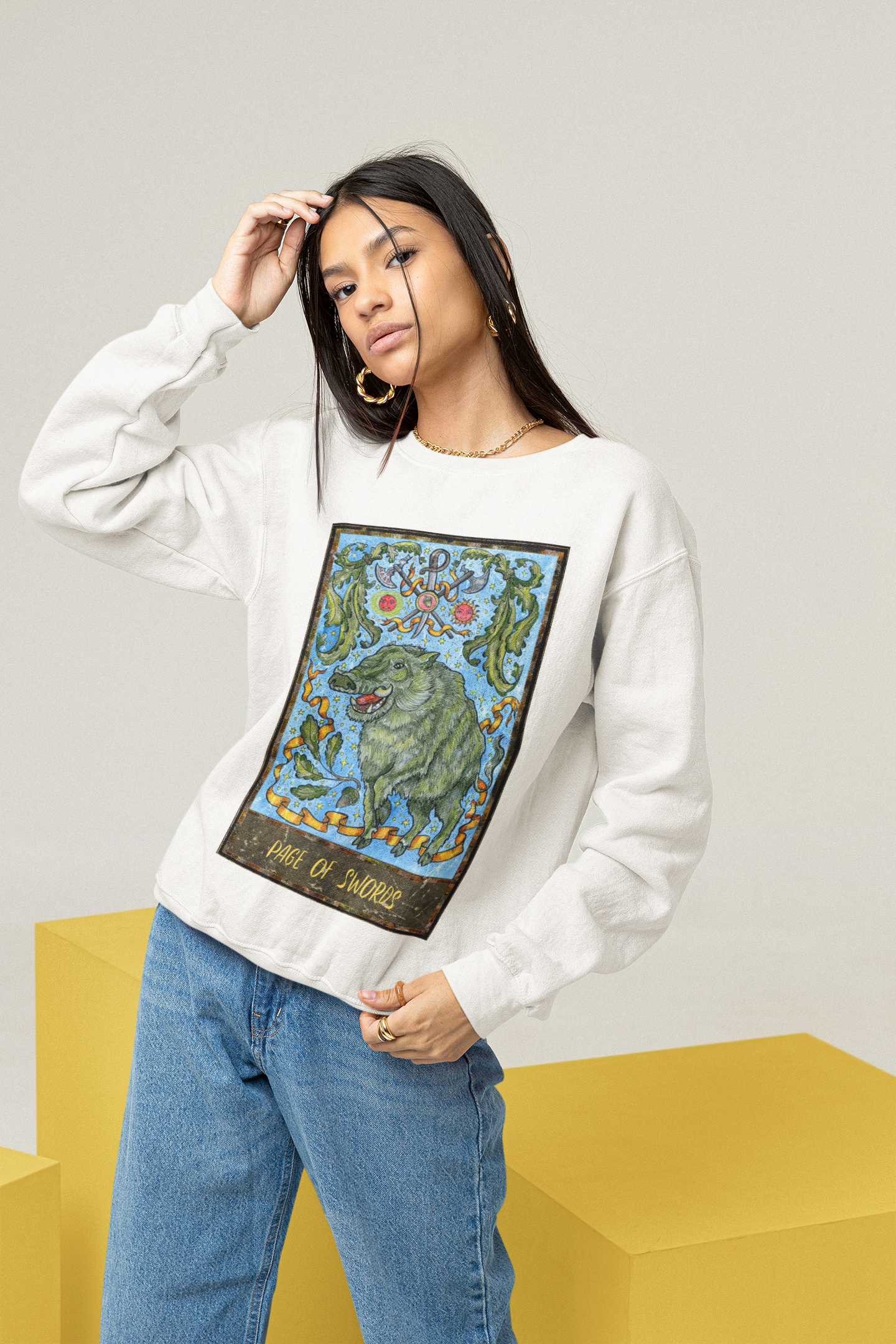 A woman wearing a white Page of Swords Tarot Card Sweatshirt and blue jeans