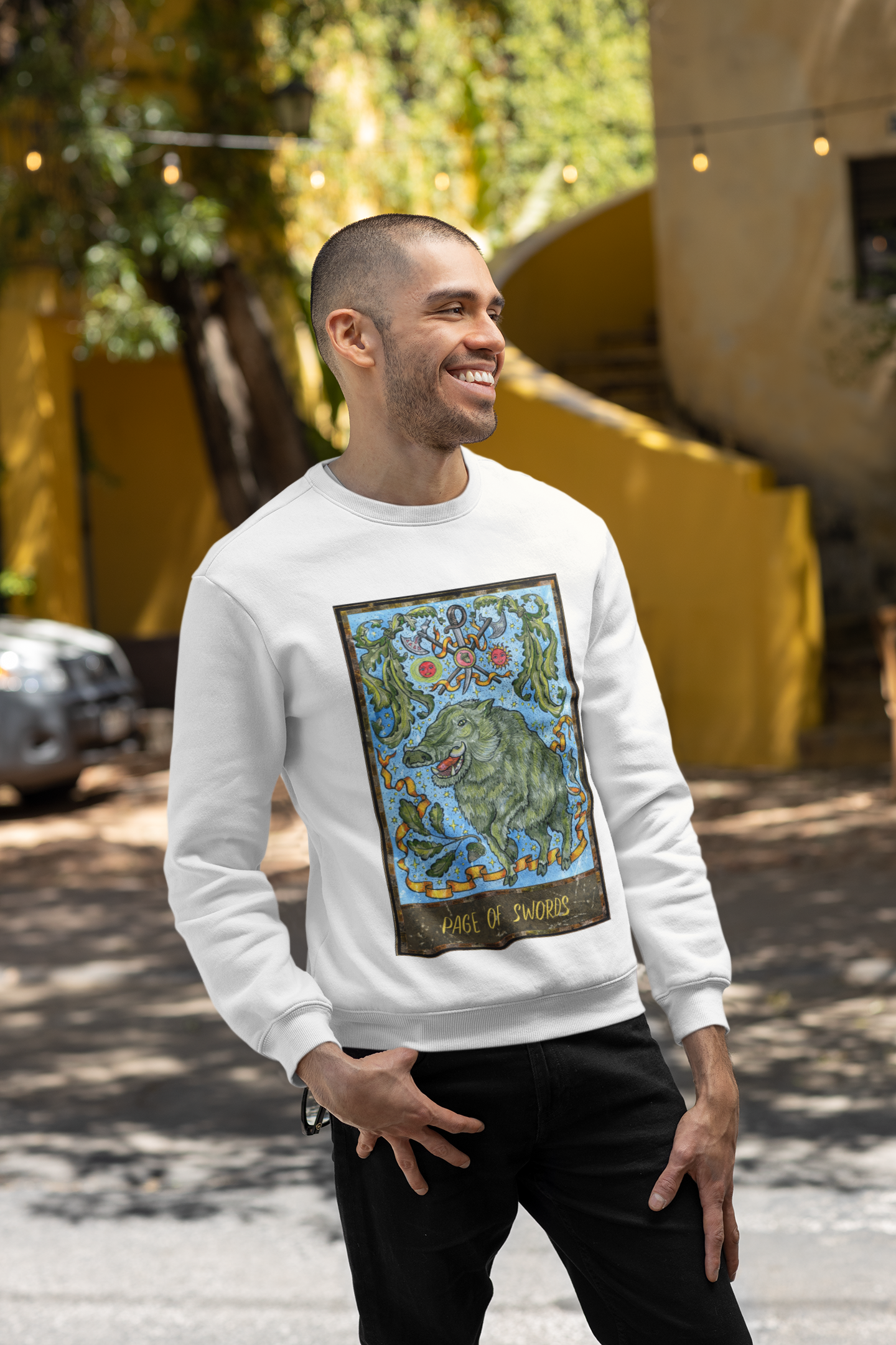 A smiling man wearing a white Page of Swords Tarot Card Sweatshirt and black pants