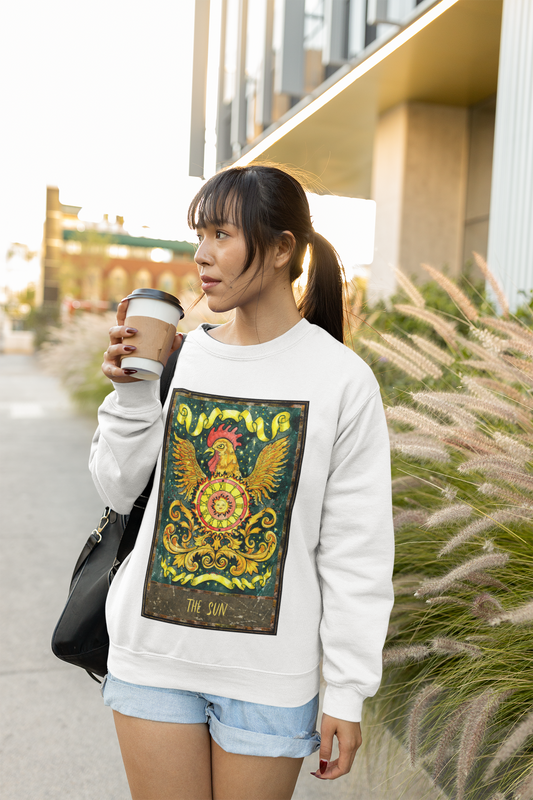 A woman drinking coffee on the street wearing a white The Sun Tarot Card Sweatshirt, blue shorts