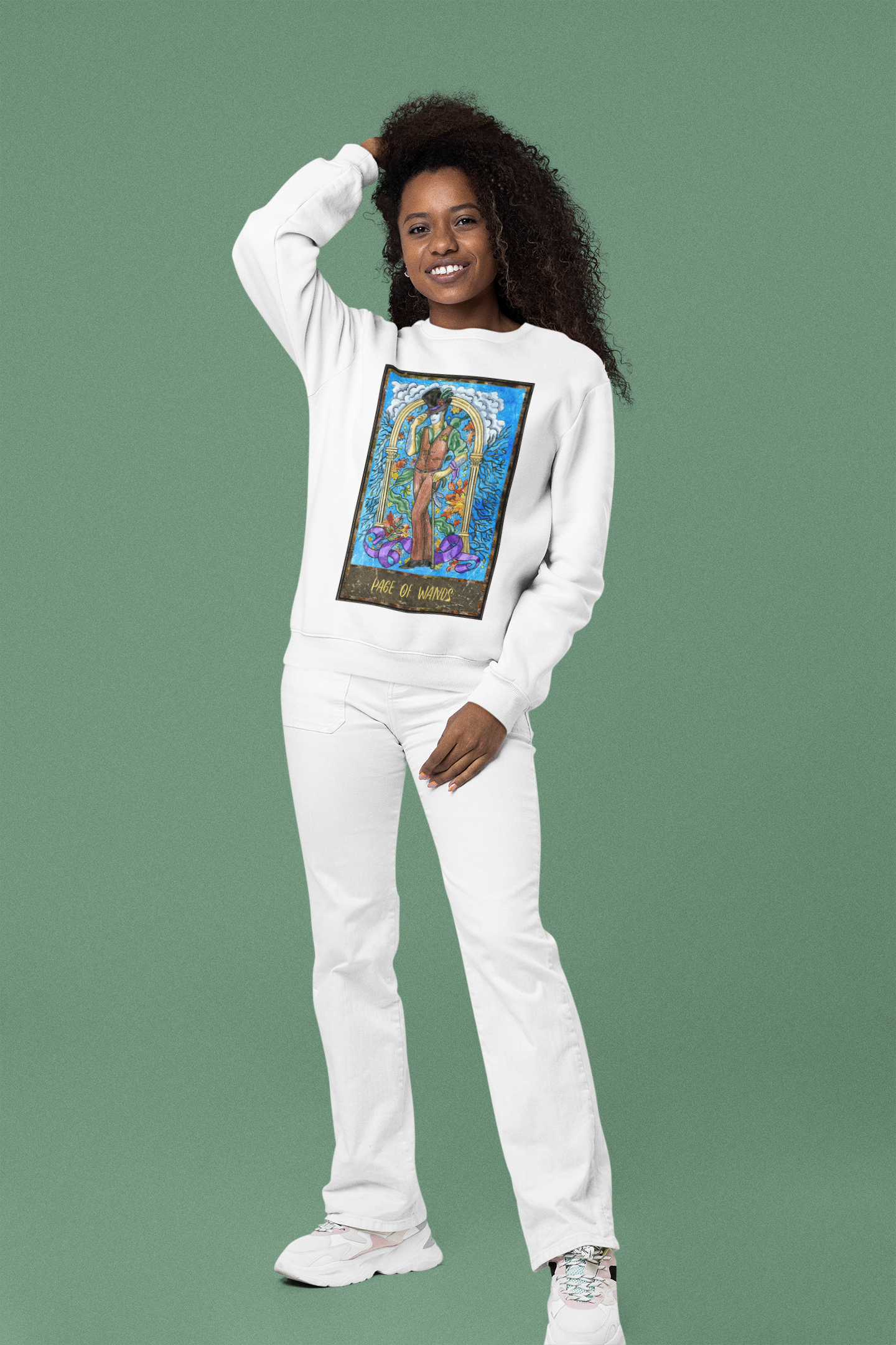 A woman wearing a white Page of Wands Tarot Card Sweatshirt, white pants and white shoes