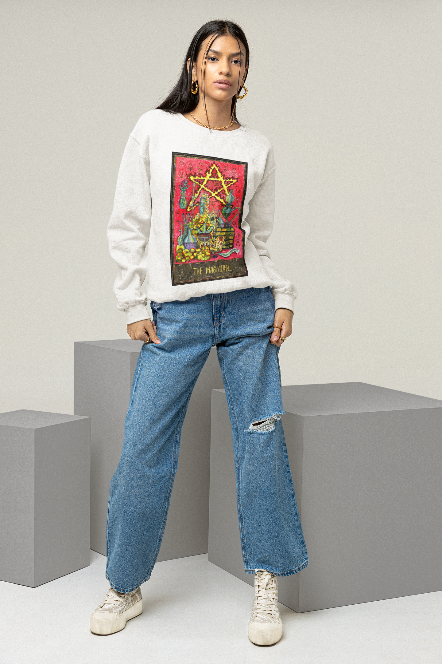 A woman wearing a white The Magician Tarot Card Sweatshirt, blue jeans and white shoes