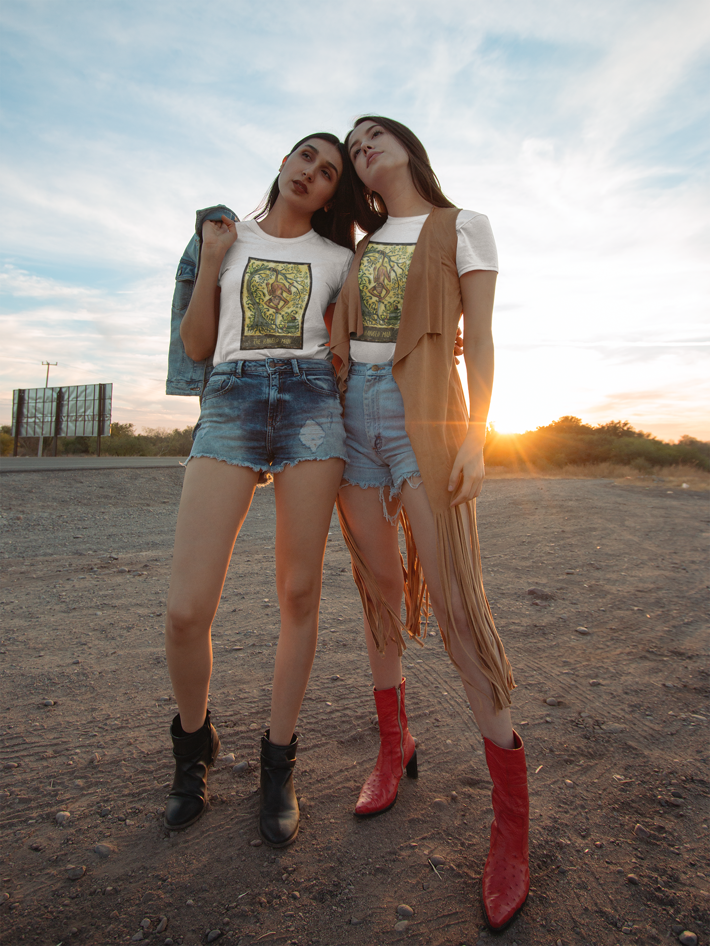 Two girls in a bohemian style wearing white The Hanged Man Tarot Card T-shirts posing by a dirt road