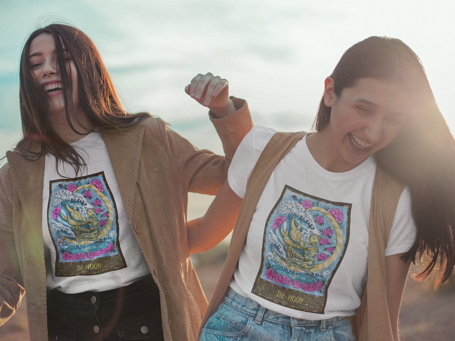 Two women laughing wearing The Moon Tarot Card T-shirts and trendy outfits