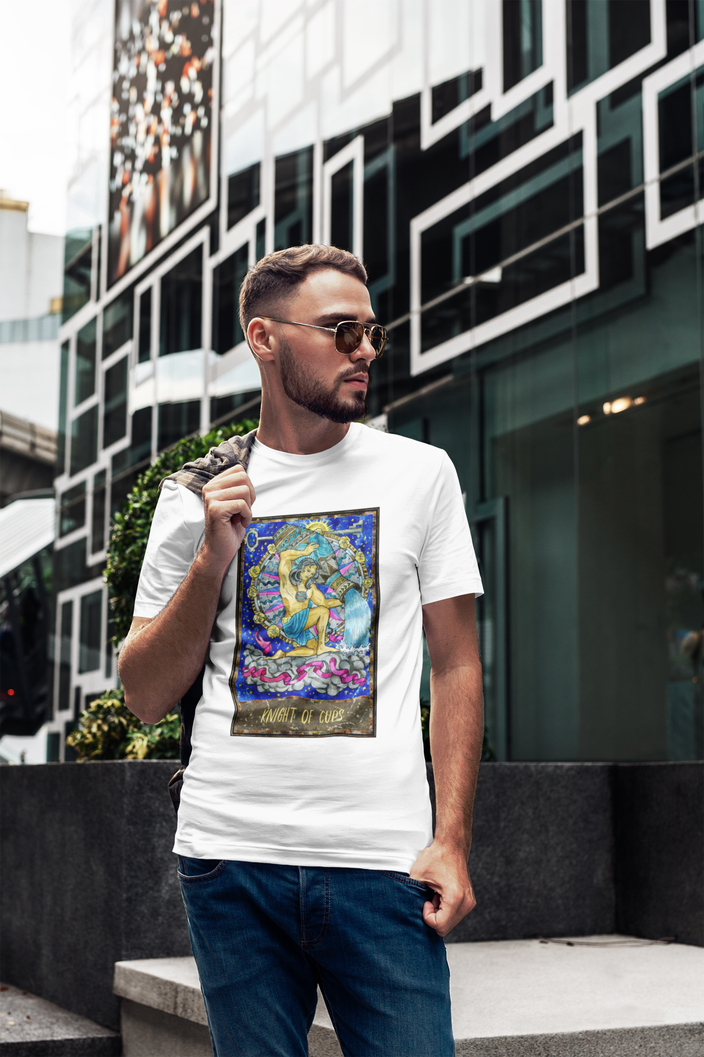 A man in sunglasses wearing a white Knight of Cups Tarot Card T-shirt, dark blue jeans