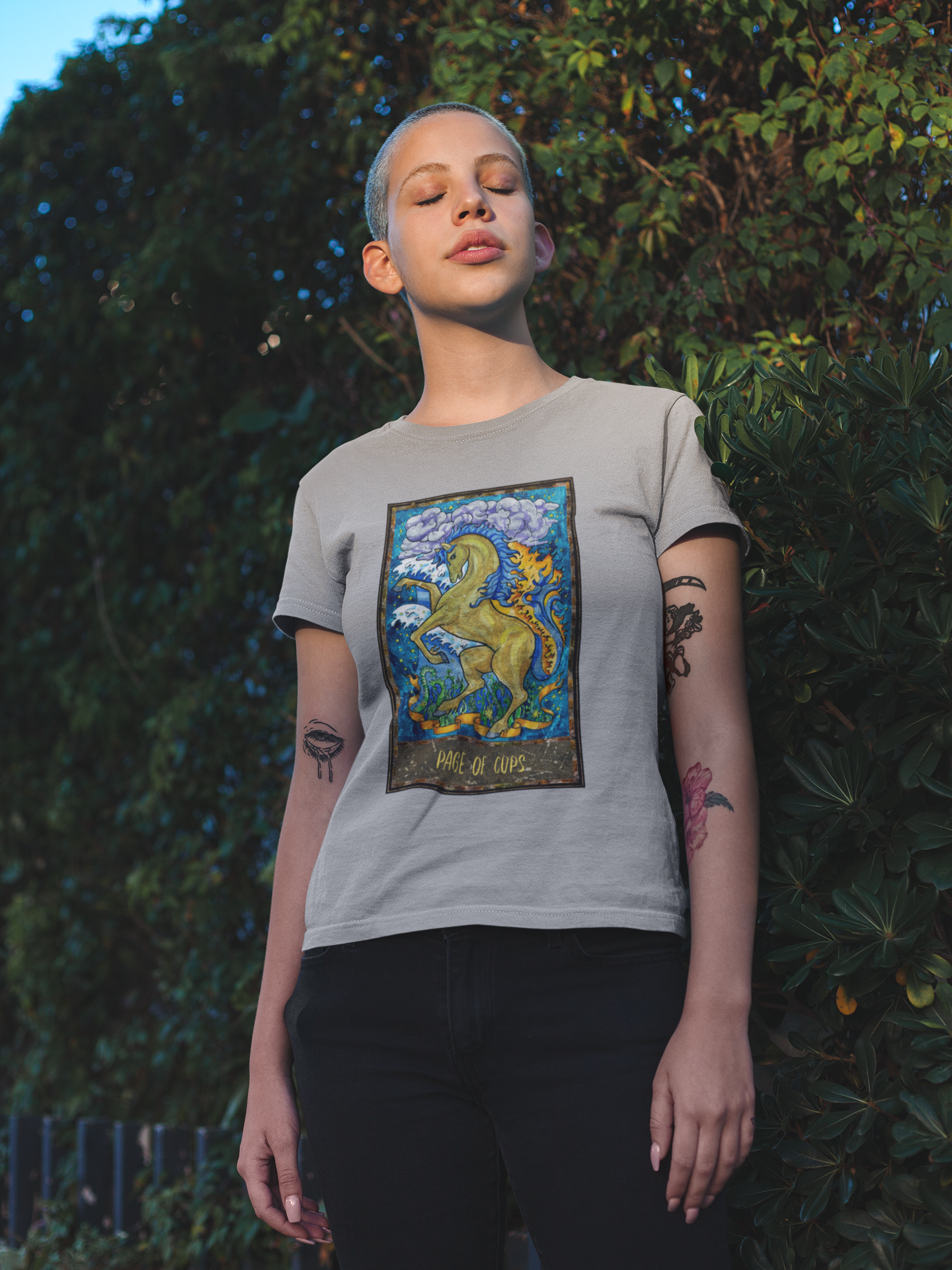 A woman wearing a grey Page of Cups Tarot Card T-shirt and black pants