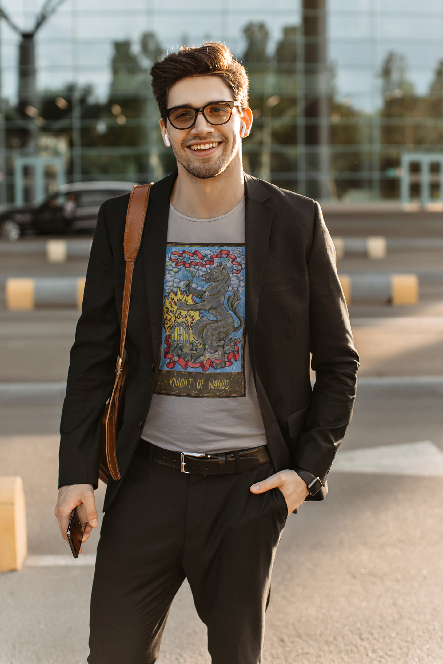 A happy man in a business casual outfit with a grey Knight of Wands Tarot Card T-shirt, black vest jacket, black pants