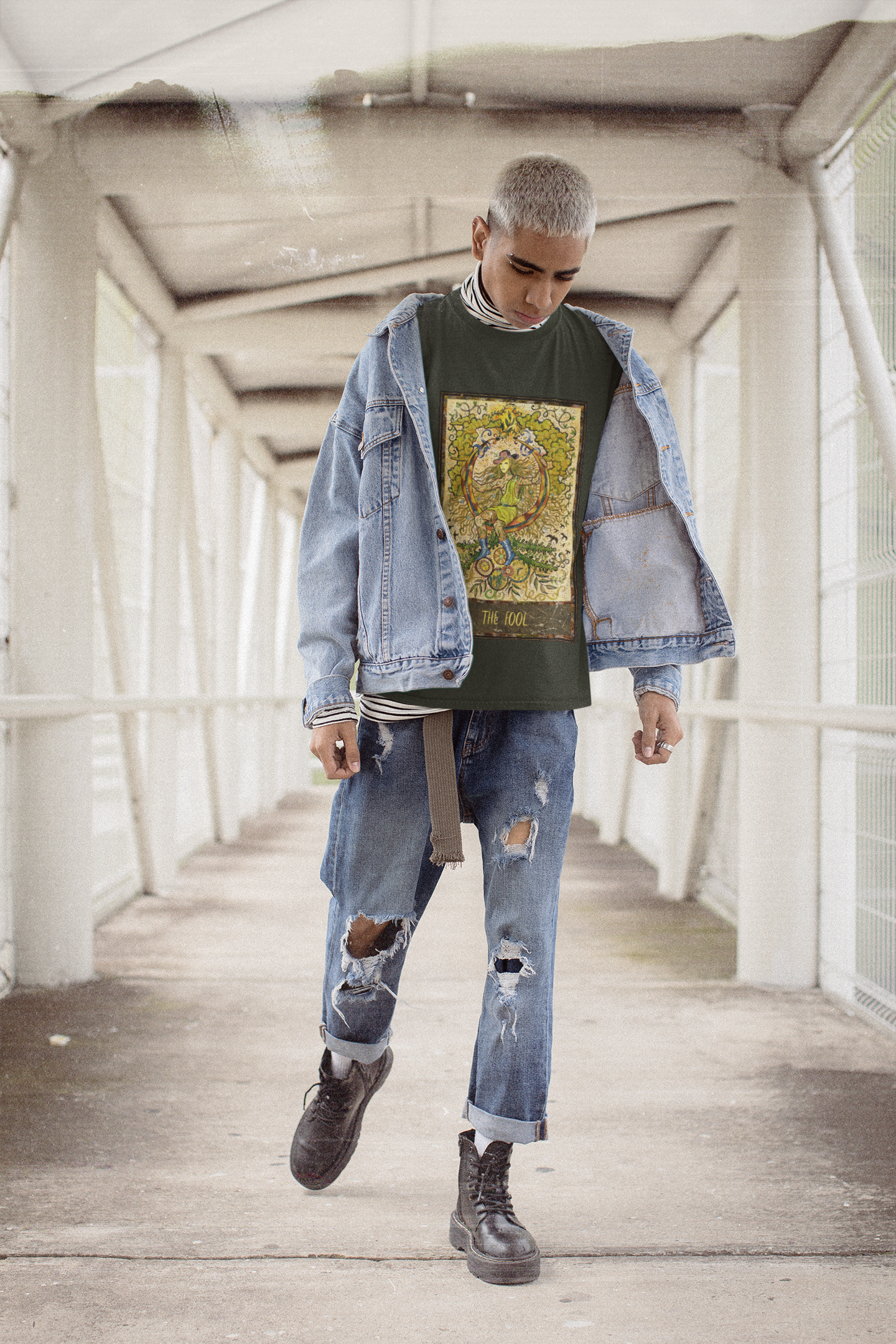 A man wearing a black The Fool Tarot Card T-Shirt with denim jacket, ripped denim jeans and black boots