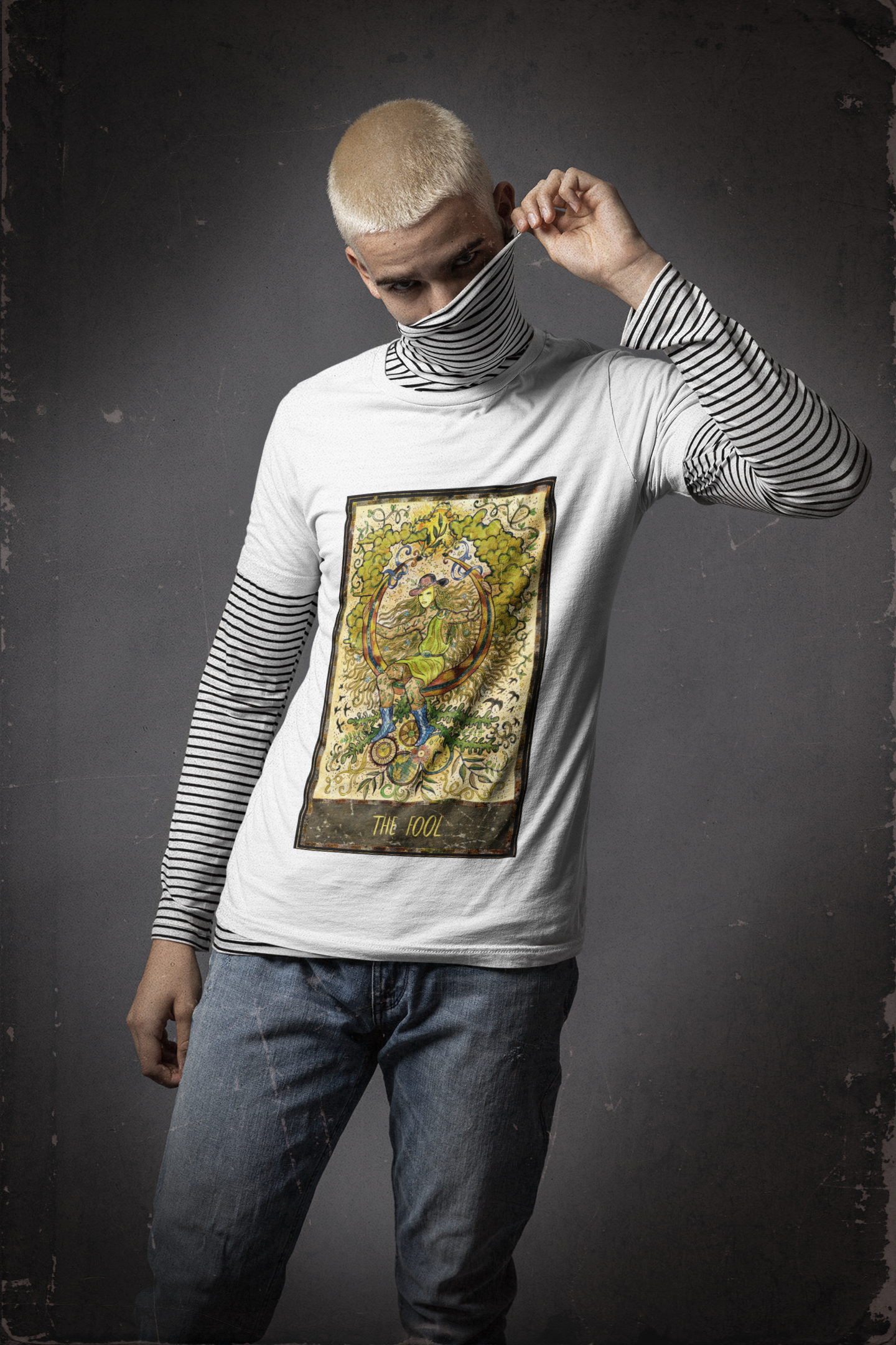 A man wearing a white The Fool Tarot Card T-Shirt with a stripe turtle neck inside, and blue jeans