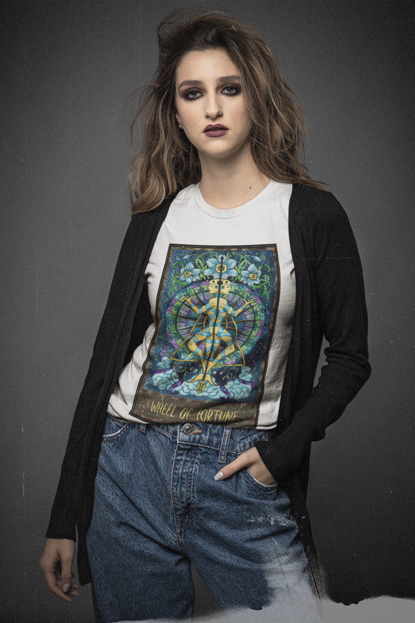 A woman wearing a white Wheel of Fortune Tarot Card T-Shirt, black cardigan, and jeans