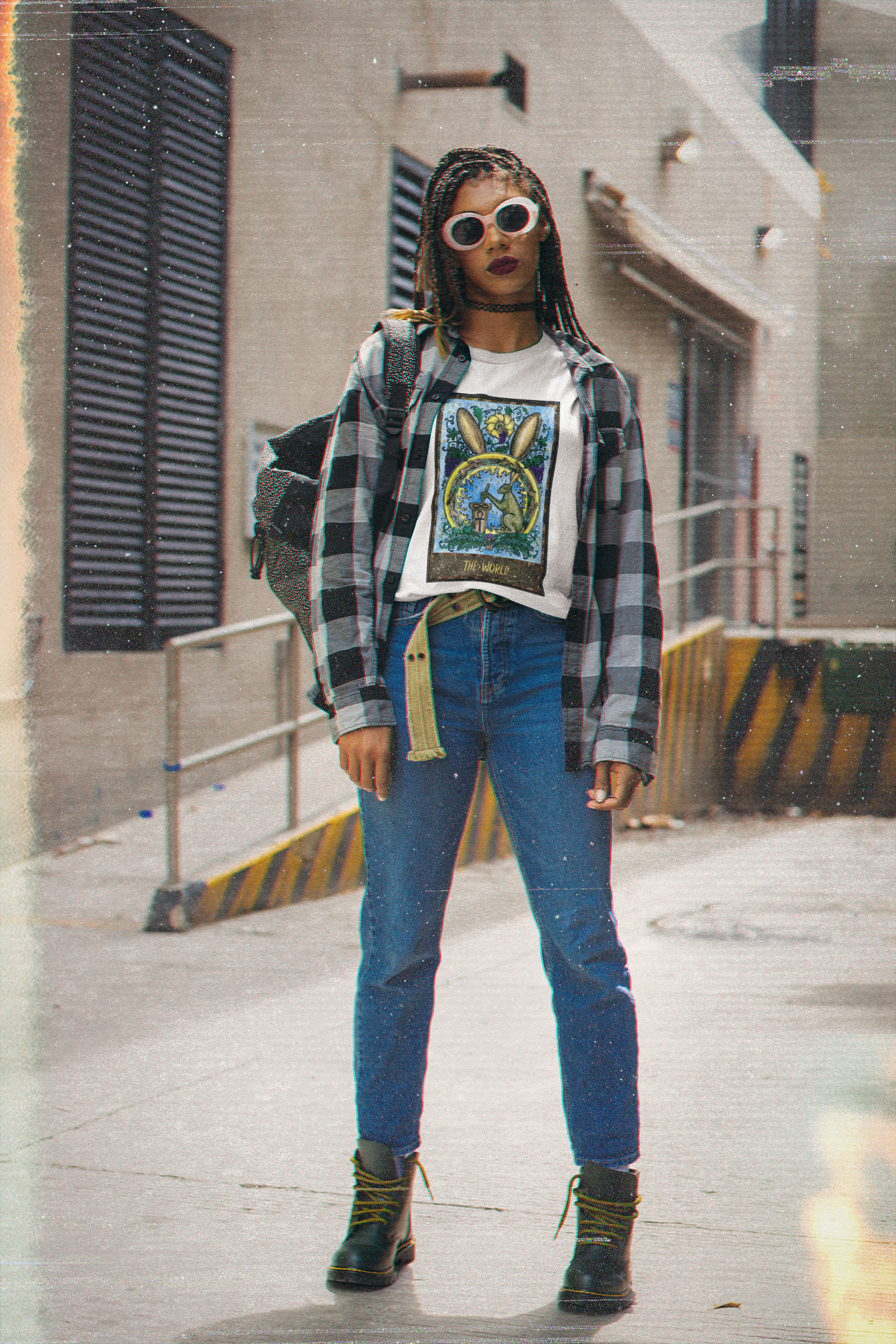 A woman with sunglasses wearing a white The World Tarot Card T-Shirt, collar outer shirt, blue jeans and black boots